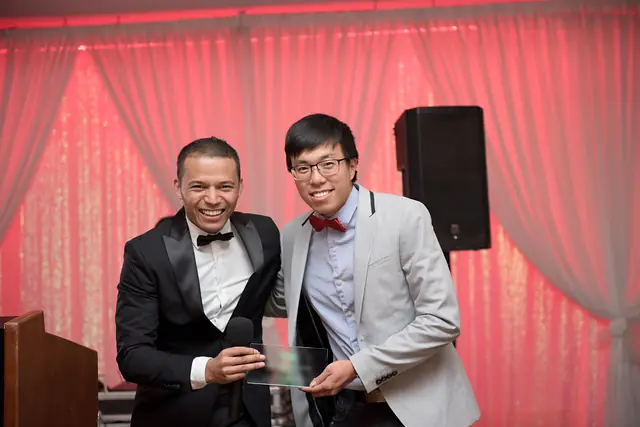 Deux hommes en tenue de soirée, tout sourire, avec un trophée