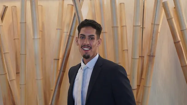 Portrait souriant d'un membre de l'équipe, devant un mur de bambous